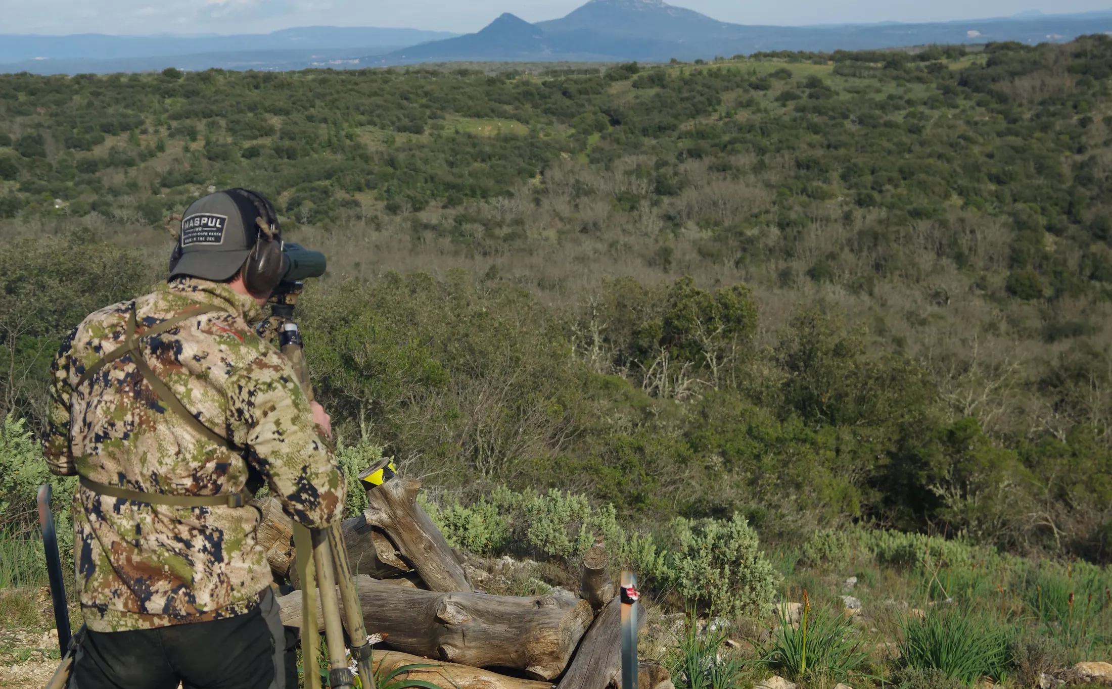 Tireur en tenue de chasse observant la vallée boisée du domaine